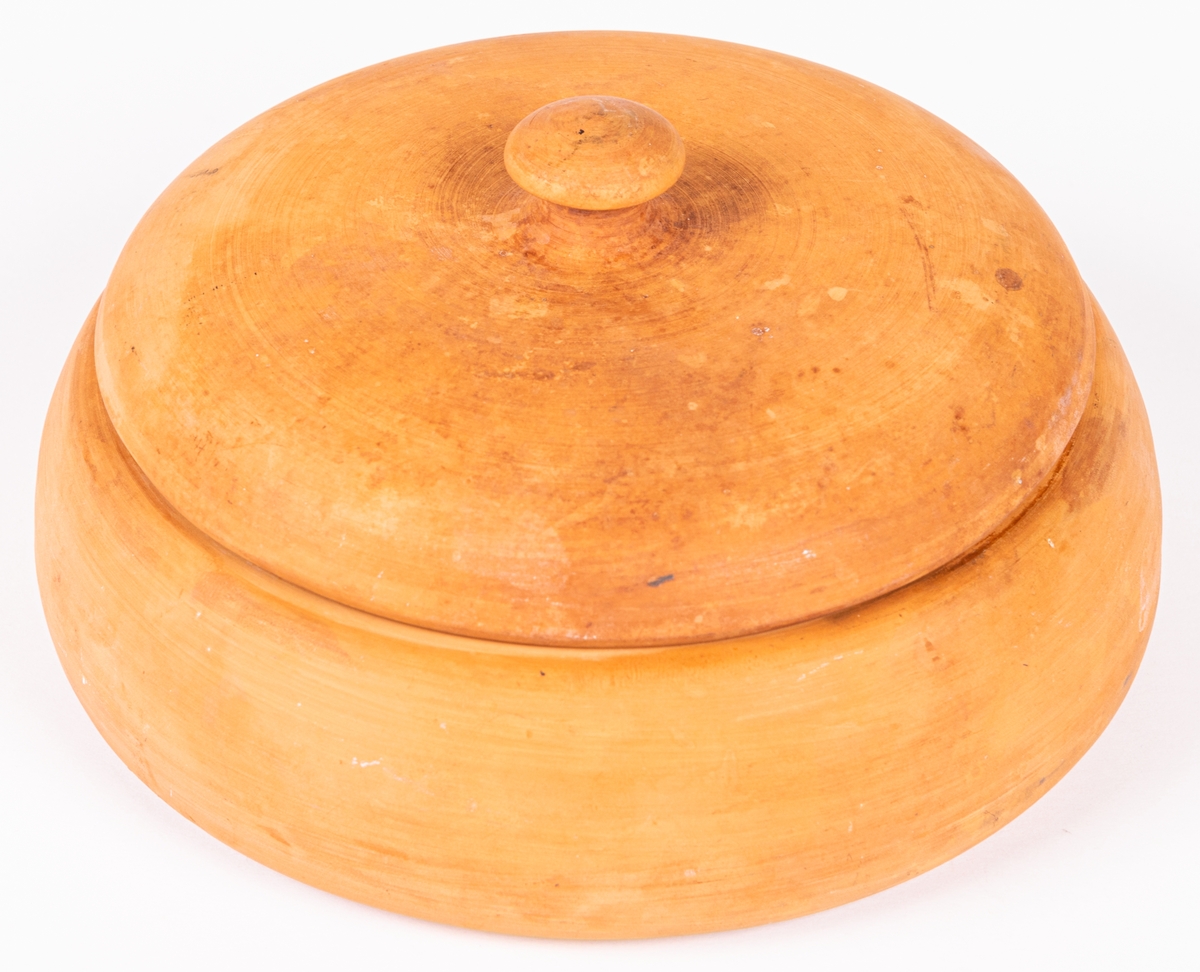 Smörkylare av oglaserad keramik, rund med lock. Kylaren saknar invändig skål för smöret, ofta i porslin eller glas. Smöret skulle ligga i porslinsskålen och runt den hälldes kallt vatten eller krossad is. Rigor är modellnamnet på kylaren.