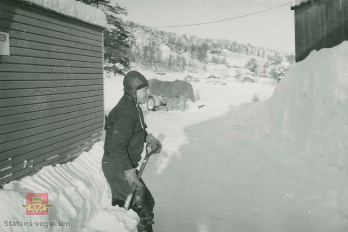 Olav Storsveen hjelper til med snømåking i brakkeleir. Snøen ble måket inntil og oppover brakkeveggene for isolering.