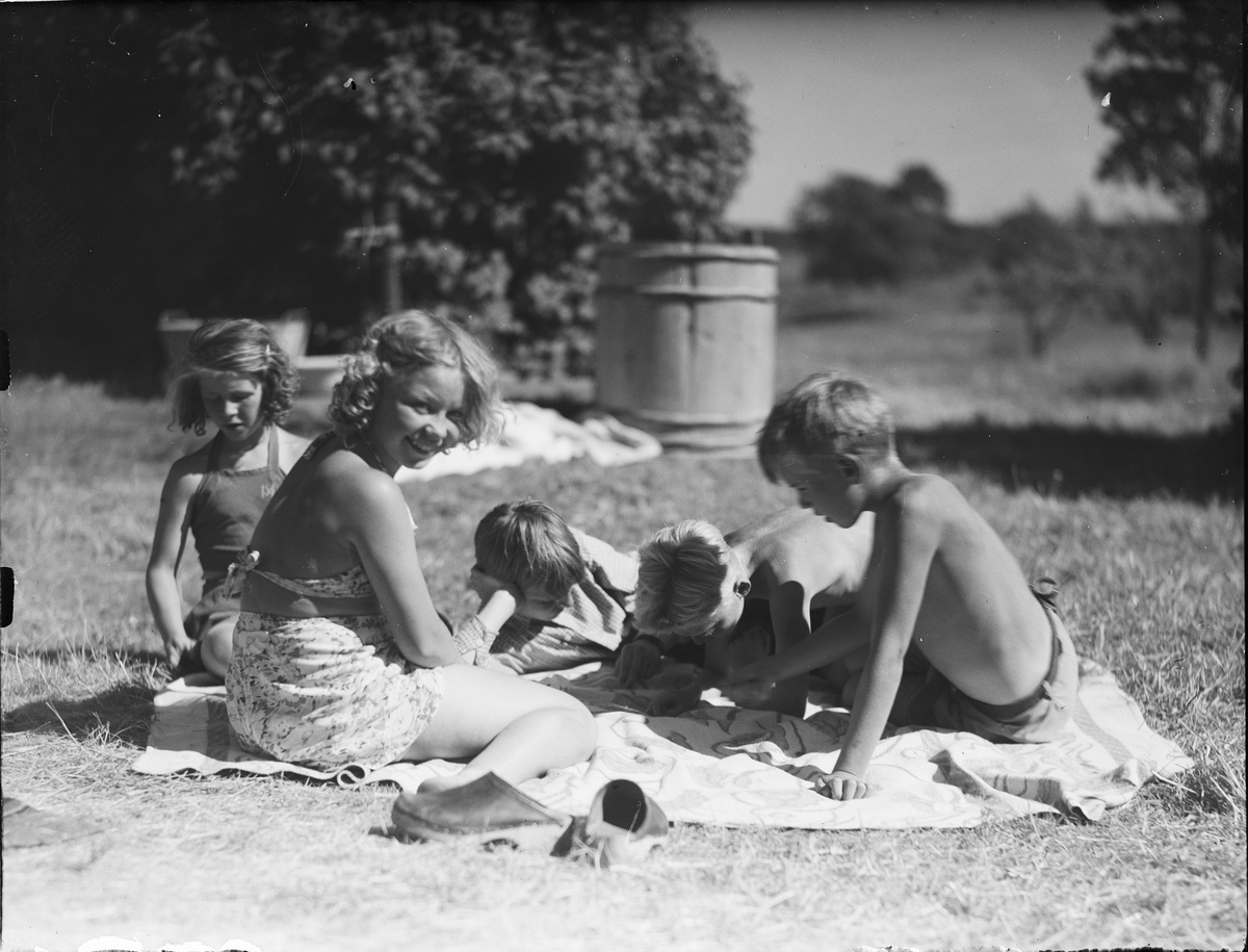Barnkoloni - barn sitter på en filt i gräset, Sandika, Harg socken, Uppland