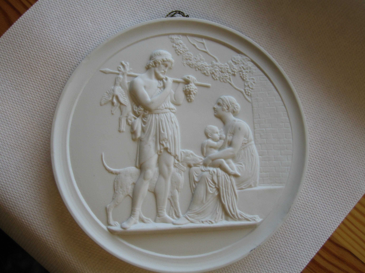 En mann og hans hund stående foran en sittende kvinne med et diende barn på fanget. Mannen holder en stav over skulderen, hvorfra det henger en hare, en fugl og en klase med druer.