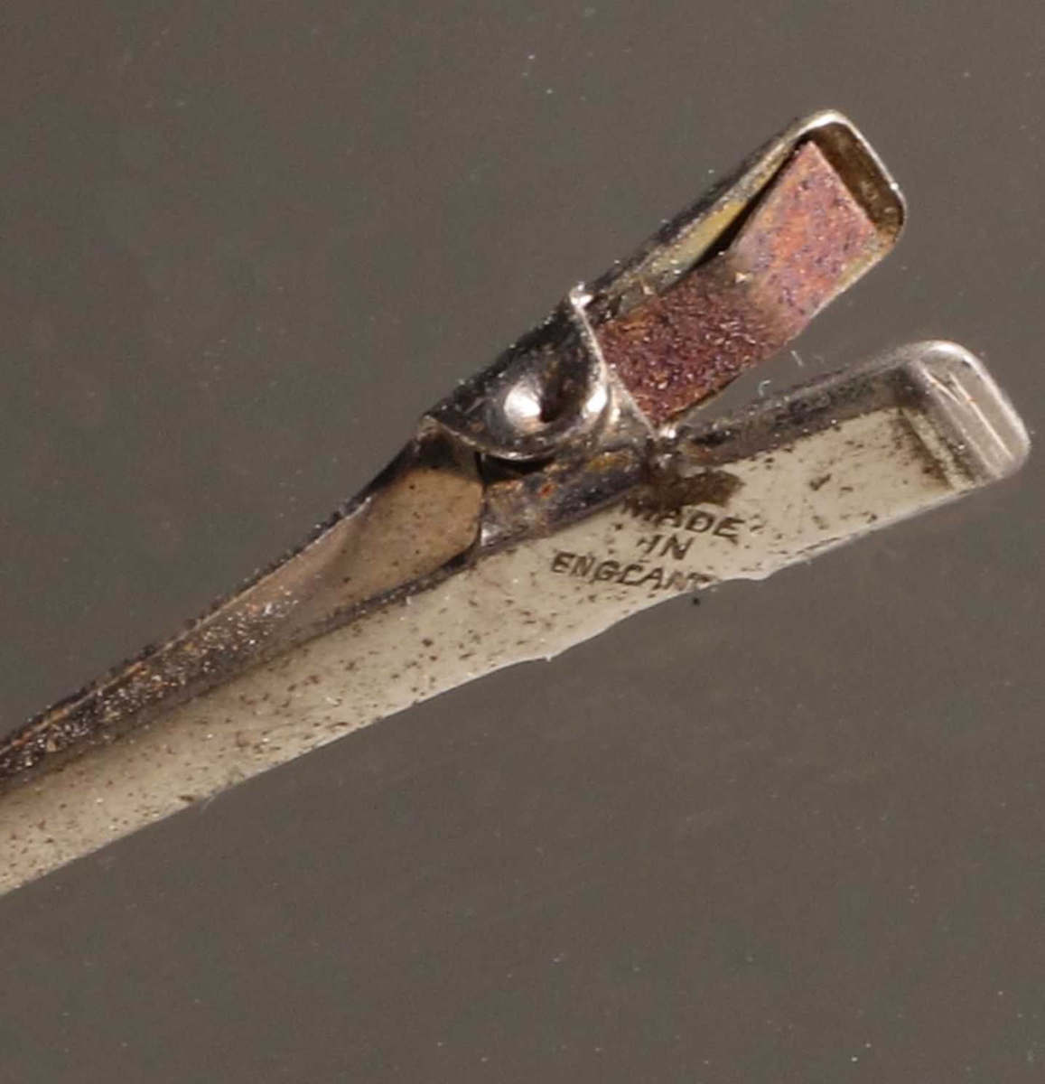 Metallspenne bestående av to deler med en liten fjær mellom "håndtakene" som holder spennen lukket.  Blikk