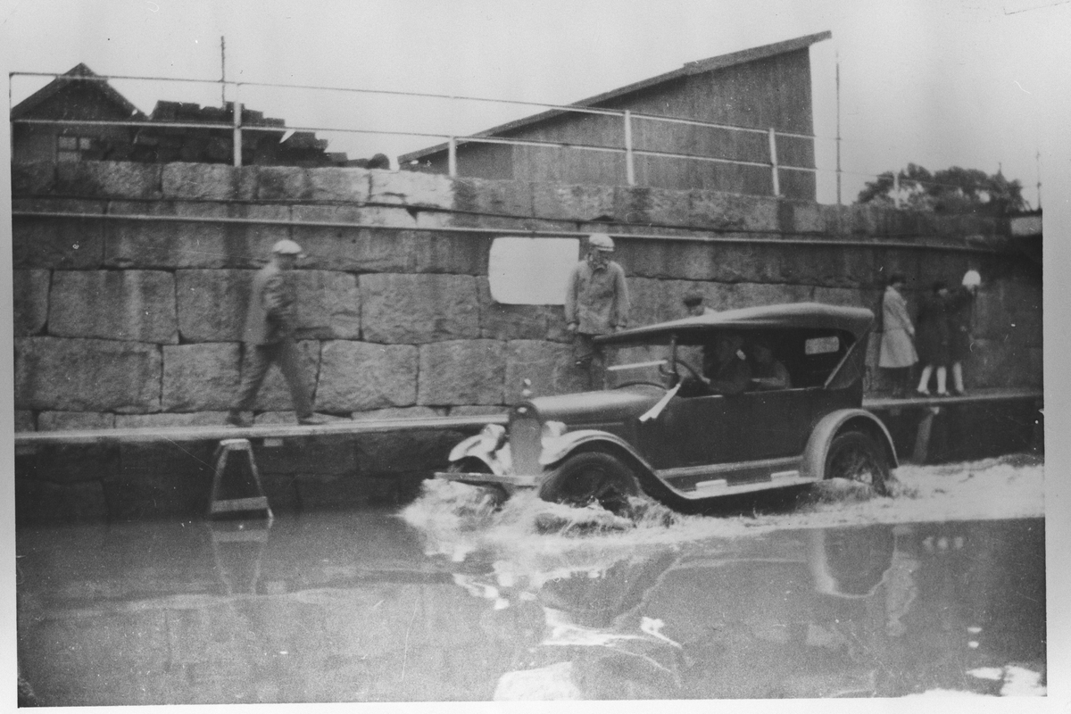 Fra flommen i 1927. Bil og personer i oversvømmet gate.
