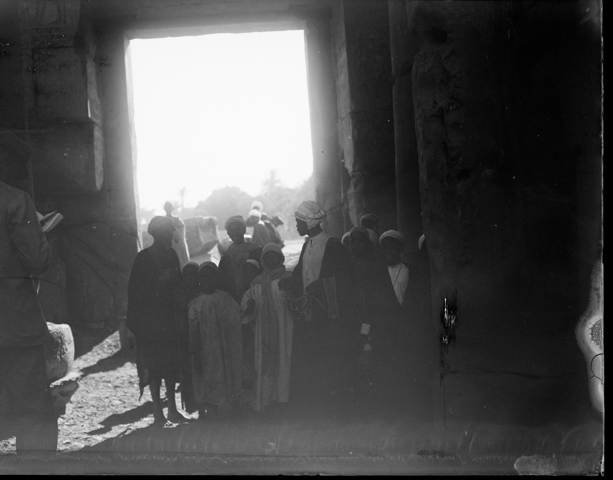 "Kournak." (Bildetekst fra album) En gruppe mennesker av lokal befolkning foran en utgang til tempelet de står i.