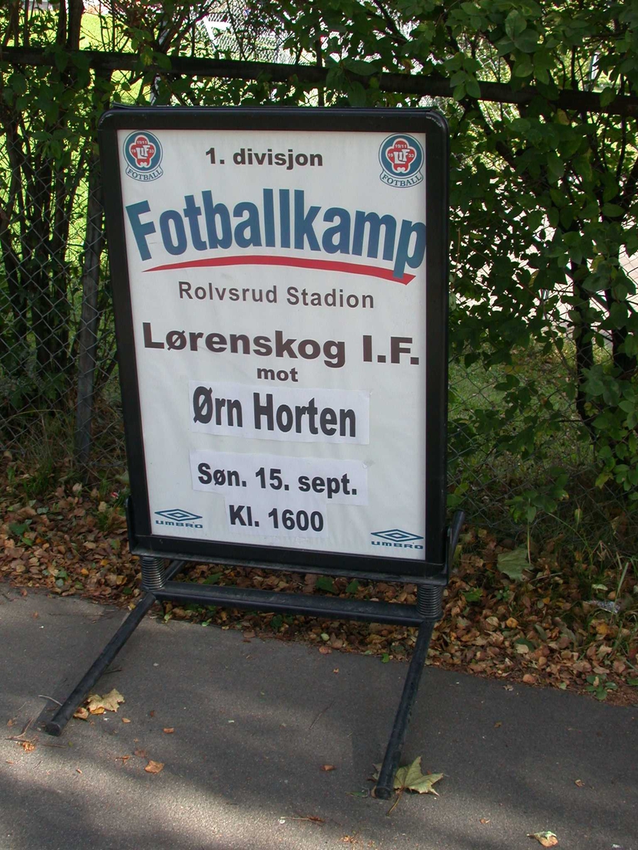 Skilt om lokal fotballkamp (1. div) på Skårersletta. Fotballkamp på Rolvsrud Stadion.
Fotovinkel: 