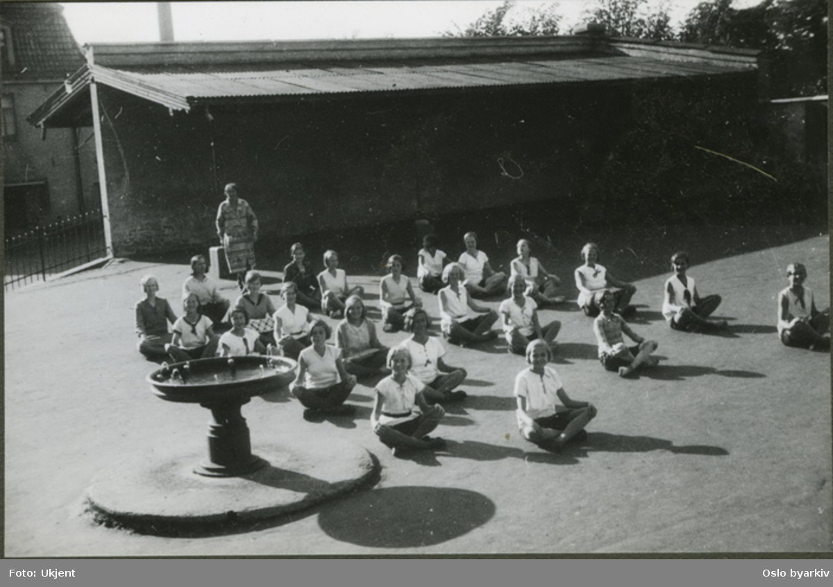 Pikeklasse i skolegården har gymnastikktime. (linjegymnastikk) Albumtittel: "Sofienberg skole femti år - første september 1933."