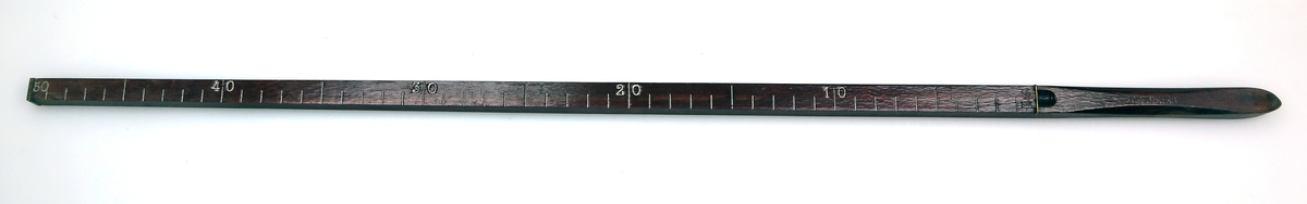 Firkantformet trestang med 50 streker med 1 cm i mellom, og håndtak som er avrundet i enden og i kantene. I motsatt ende er det skrudd på en liten messingplate. Treverket er lakkert