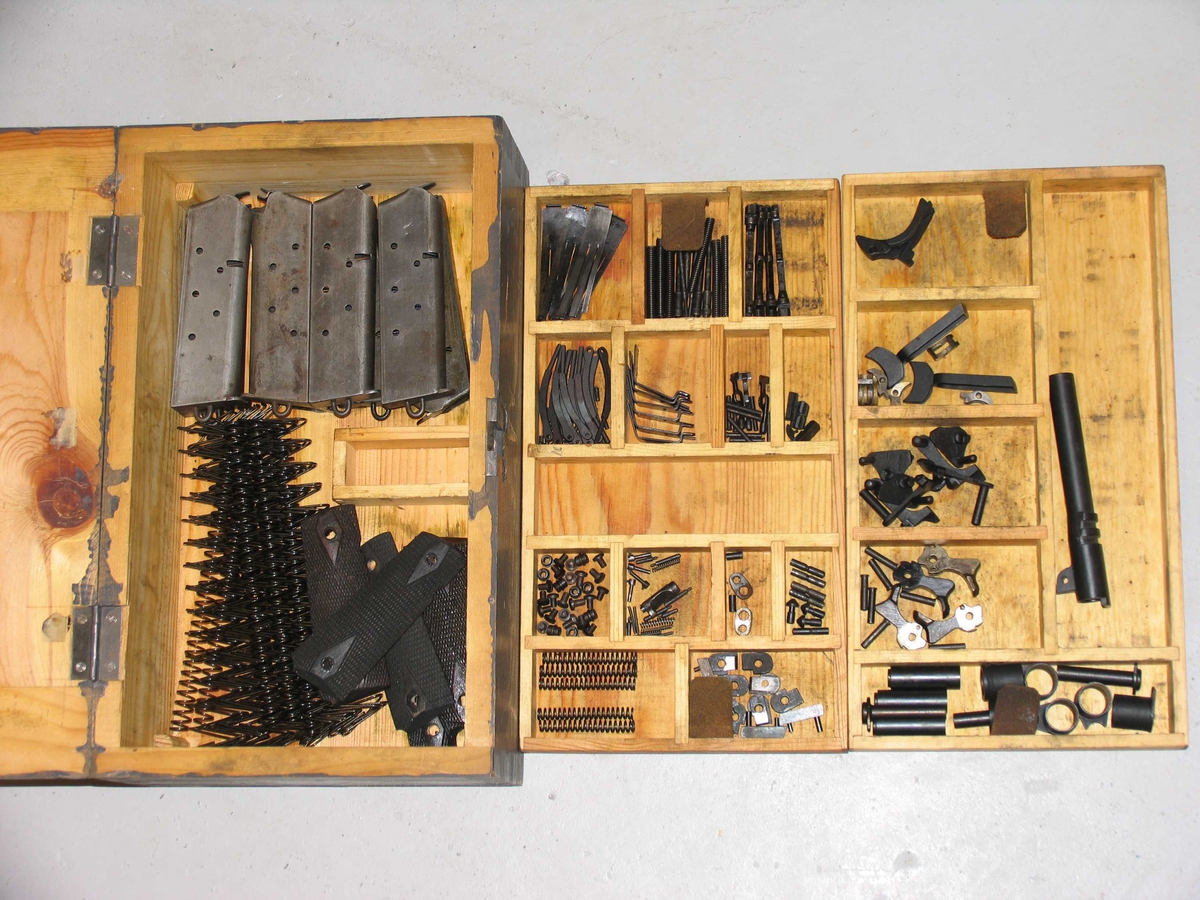 Reservedelskasse for Colt pistol, laget etter modell av den Norske førkrigsmodell. Innholdet er sammenfallende i disse kassene. Gråmalt.