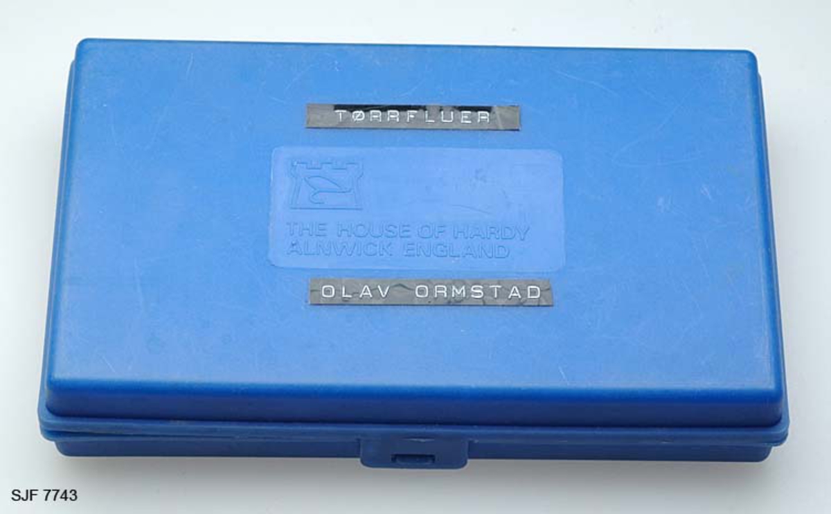 Tilstand: I forbindelse med omfotografering av gjenstander høsten 2002, oppdaget OT Ljøstad at fluene i denne esken var langt på veg ødelagte av møllangrep.  Problemet skyldes at gjenstanden har vært lagret i magasin C, der temperaturen er såpass høy at møllen trives. 
Boksen inneholder ialt 75 stk tørrfluer. Tørrfluene har den funksjon at de flyter på vannet, derfor så bustete. En meget fin boks som en setter fluene fast i, istedenfor at de ligger hulter i bulter. Giveren har skrevet ei bok med navnet "Isfiske" sammen med Knut Rom, boka ble utgitt i 1972. Giverens far var en ivrig sportsfisker og ble gitt tittelen "Den fullendte sportsfisker". 

Boksen inneholder ialt 75 stk tørrfluer. Tørrfluene har den funksjon at de flyter på vannet, derfor så bustete. En meget fin boks som en setter fluene fast i, istedenfor at de ligger hulter i bulter. Giveren har skrevet ei bok med navnet "Isfiske" sammen med Knut Rom, boka ble utgitt i 1972. Giverens far var en ivrig sportsfisker og ble gitt tittelen "Den fullendte sportsfisker". 
