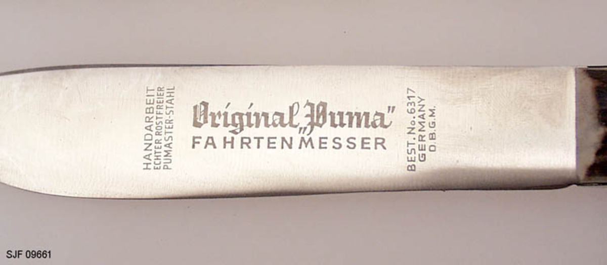 Kniven sitter fast i slira ved at et hull i knivskaftet hvor det er tredd ei reim som er festet til slira. 