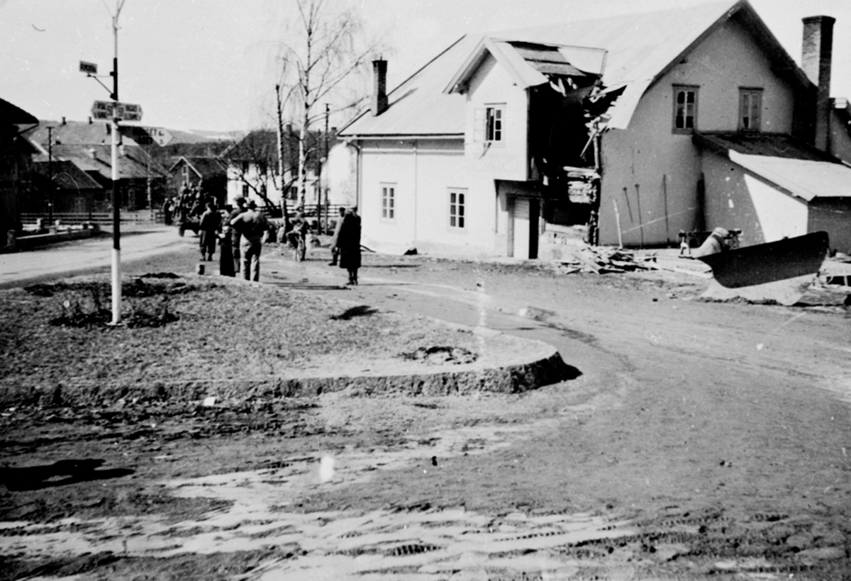 Buttekvern mølle, Brumunddal, truffet av granater under krigen, 19. april 1940, folk ser på tyske soldater som passerer.