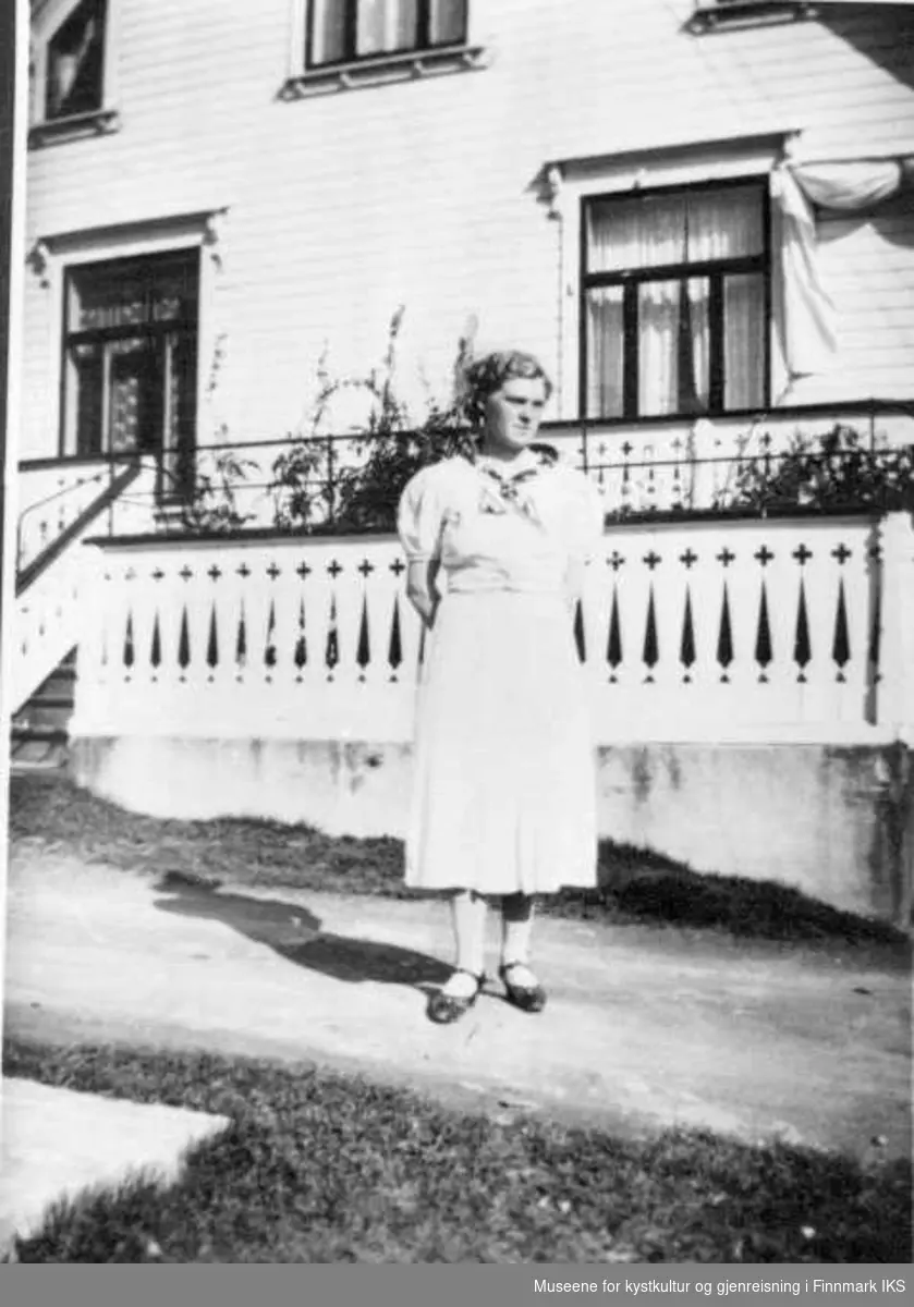 Edith Endresen (Neshaug) utenfor Grebstadgården. Edith har kjole som er sydd av hvite melsekker, ca 1937