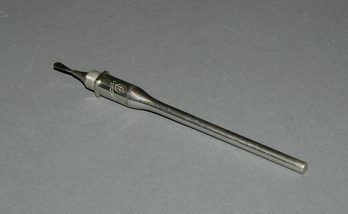 Holder med snitting, lansetten kan skrues av, vendes og oppbevares inne i holderen. Holder/en metallstangen er tykkere og uthulet i ene enden. 