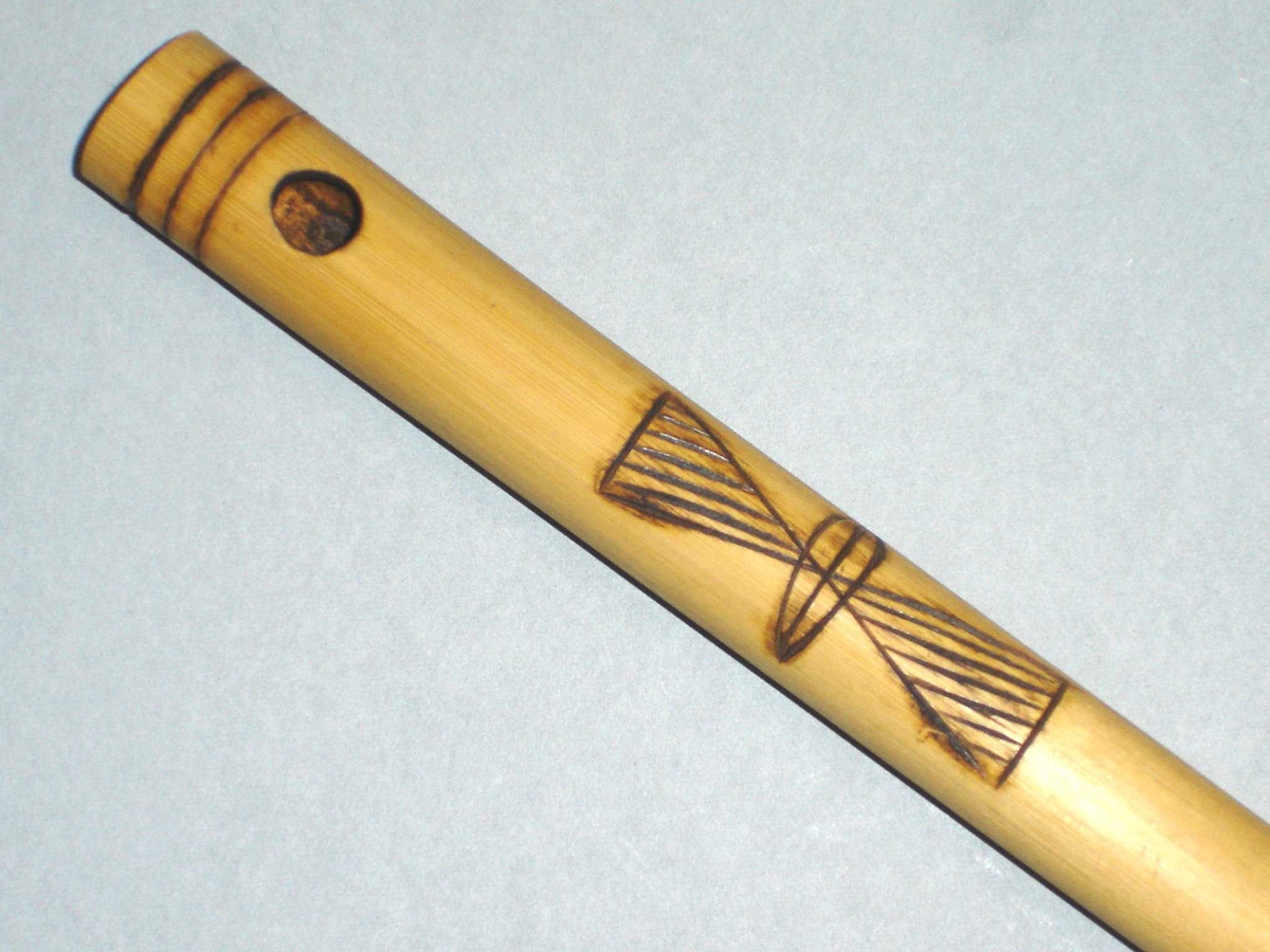 Fløyte i bambus med seks fingerhull og ett blåsehull. Innbrent dekor.