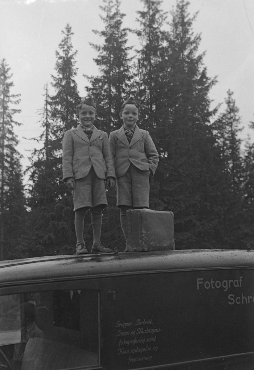 John og Ole Evjen stående på taket av fotograf Schrøders bil. Skal illudere å stå på et fly.