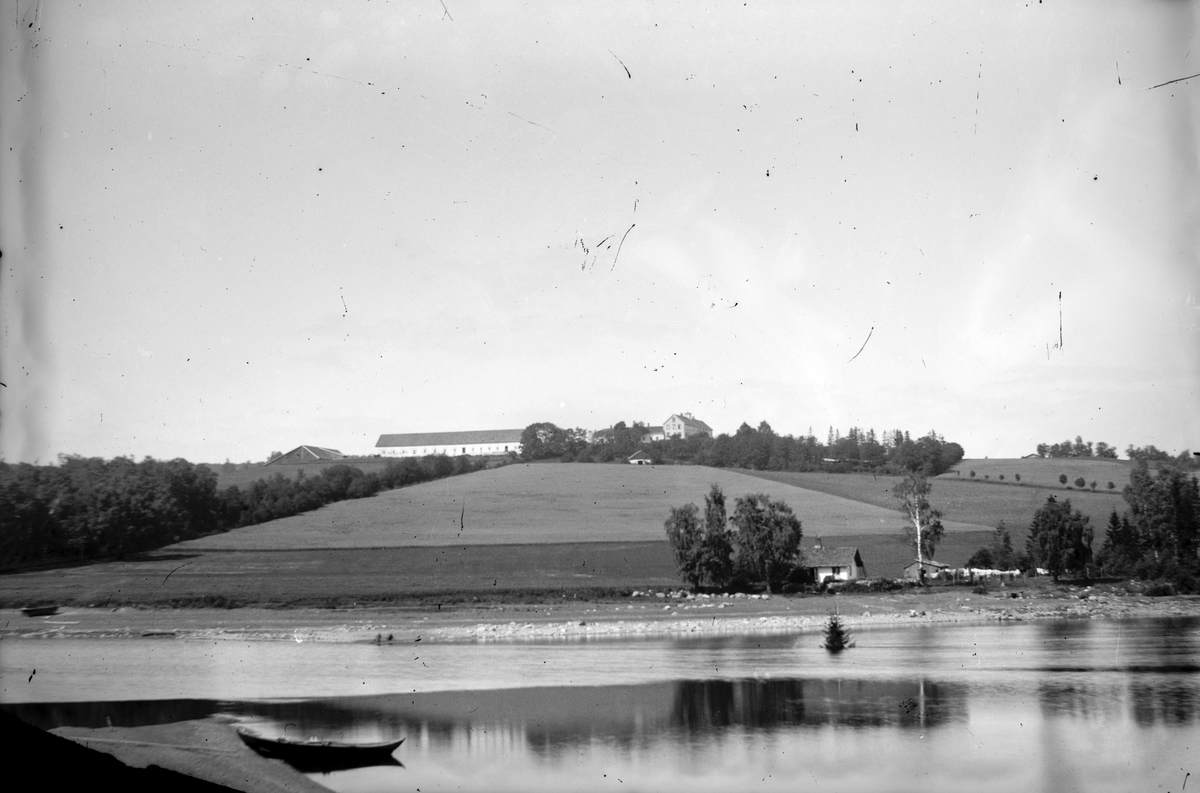 Hovinsholm gård, Helgøya i Ringsaker. Gården med Holmstøen sett fra Hovinsholmen. Foto Jacob Hoel 10. 06. 1887. 