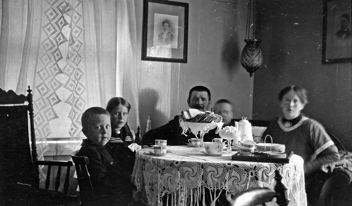 Familien Ole J. Gunnerød ved kaffebordet. De to voksne er Ole og Olave Gunnerød, barna fra venstre: Lars, Aslaug, og John.