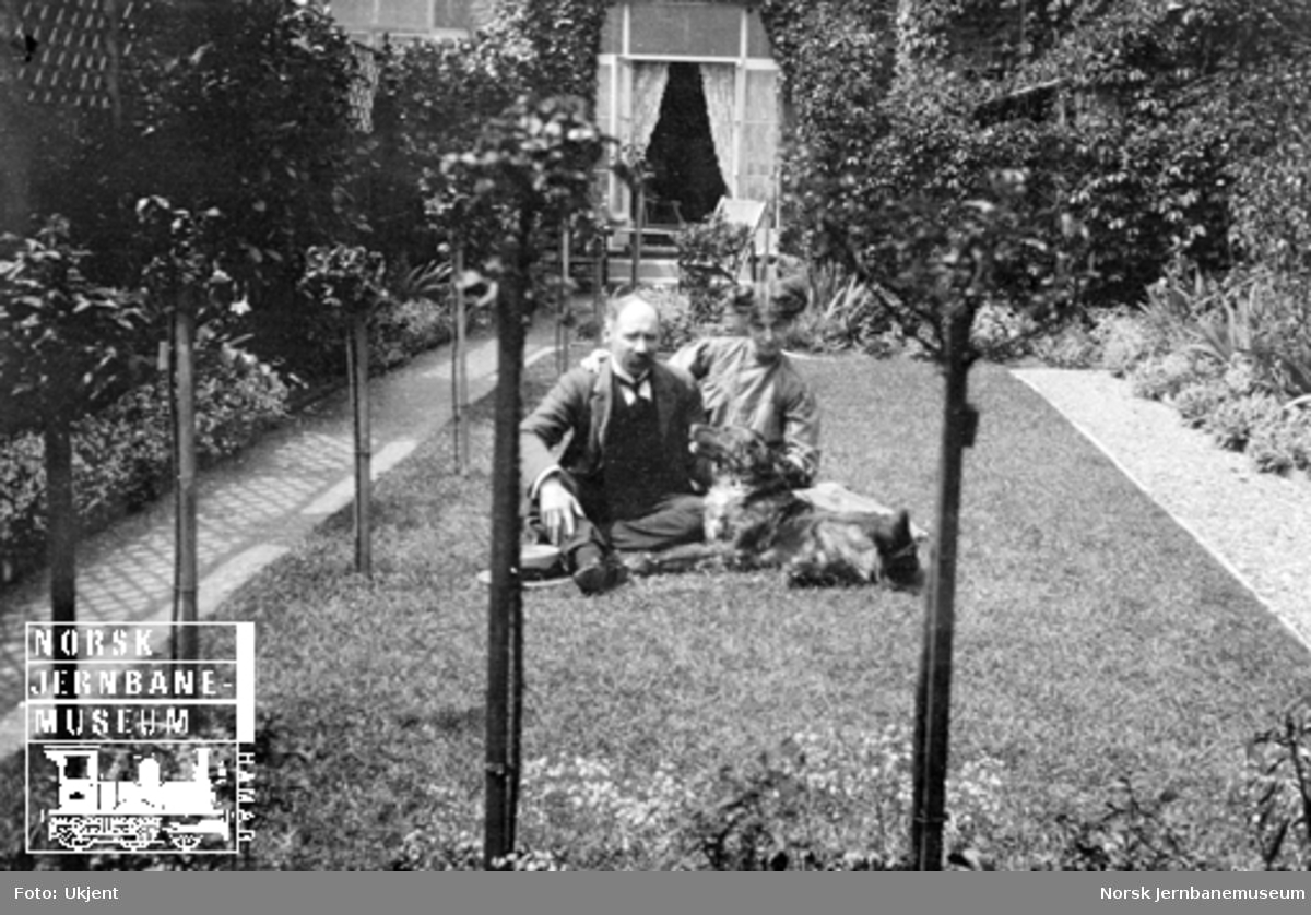Familiebilder : et par med hund på gressplenen foran huset