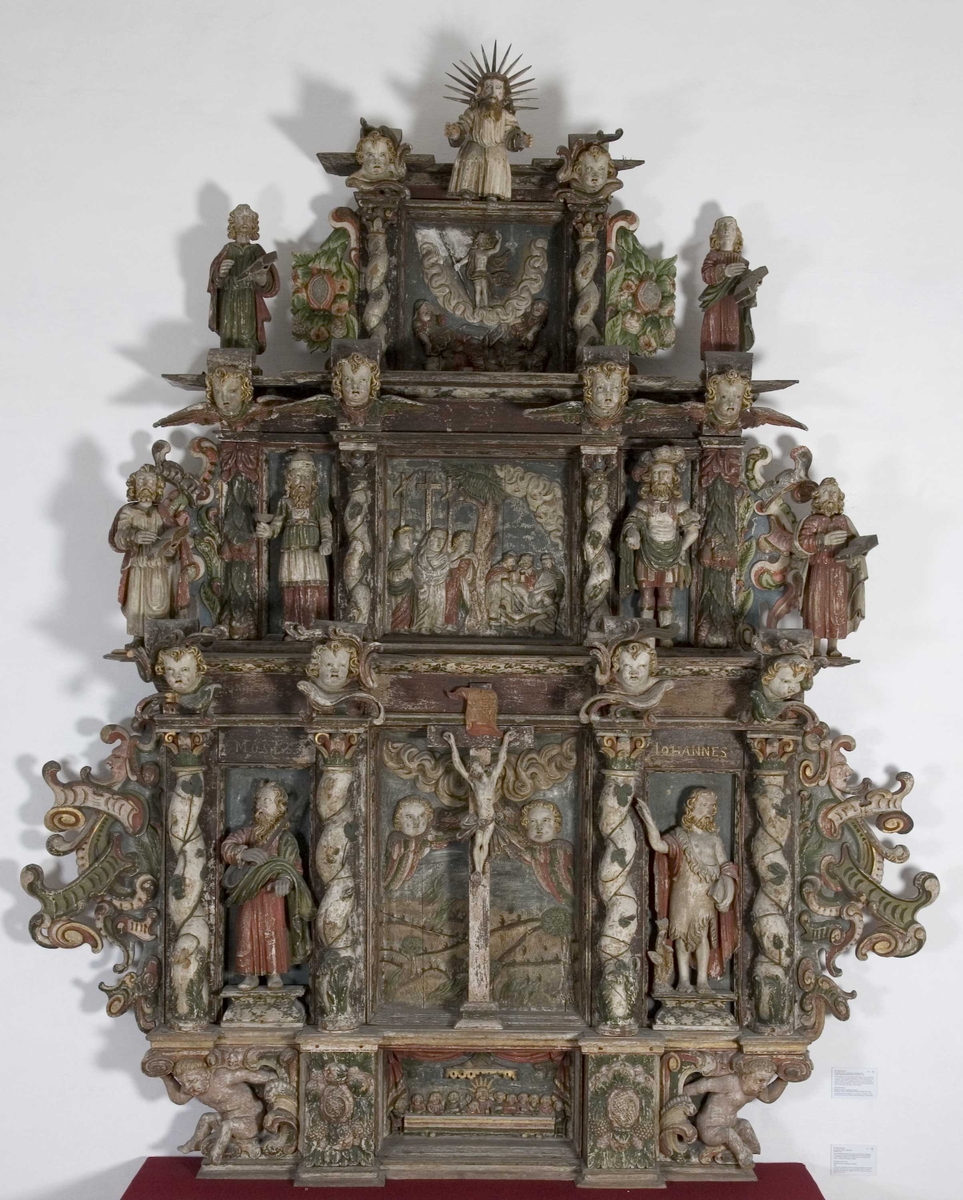 Nedenfra ser vi nattverden, den korsfestede Kristus flankert av Moses og Johannes, begravelsen, oppstandelsen og øverst Kristus som Salvator Mundi, Verdens Frelser. De fire figurene som holder hver sin bok, forestiller sannsynligvis de fire evangelistene. 