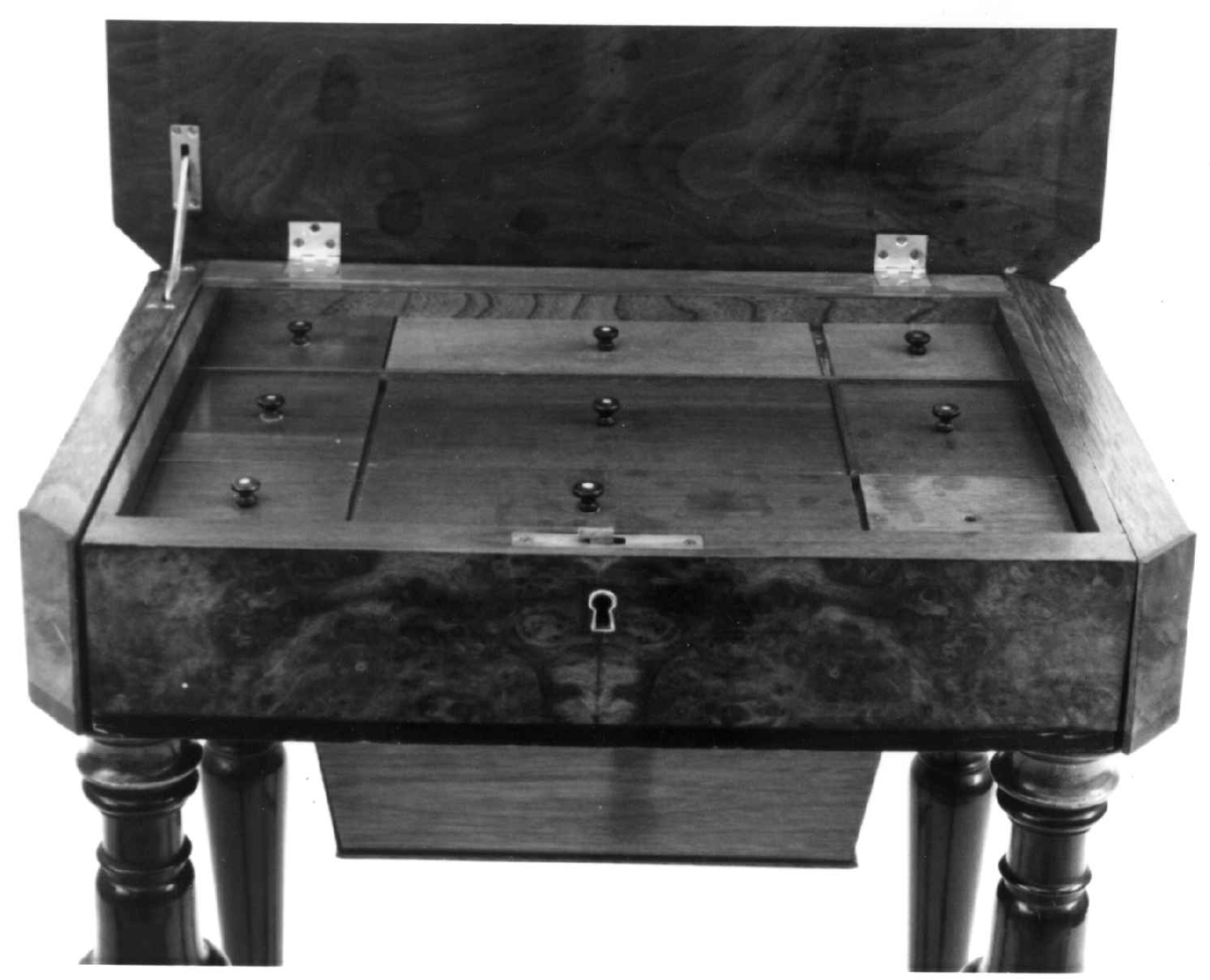 Åtte-kantet sybord med rotfiner i nøttetre. Dreide ben og bindingssprosser. Innvendig skuff med 9 rom og lokk.