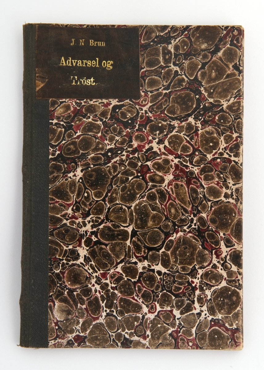 Tynn bok med marmorert papirtrekk i brunt, rødt og gulhvitt. Mørkebrun rygg.