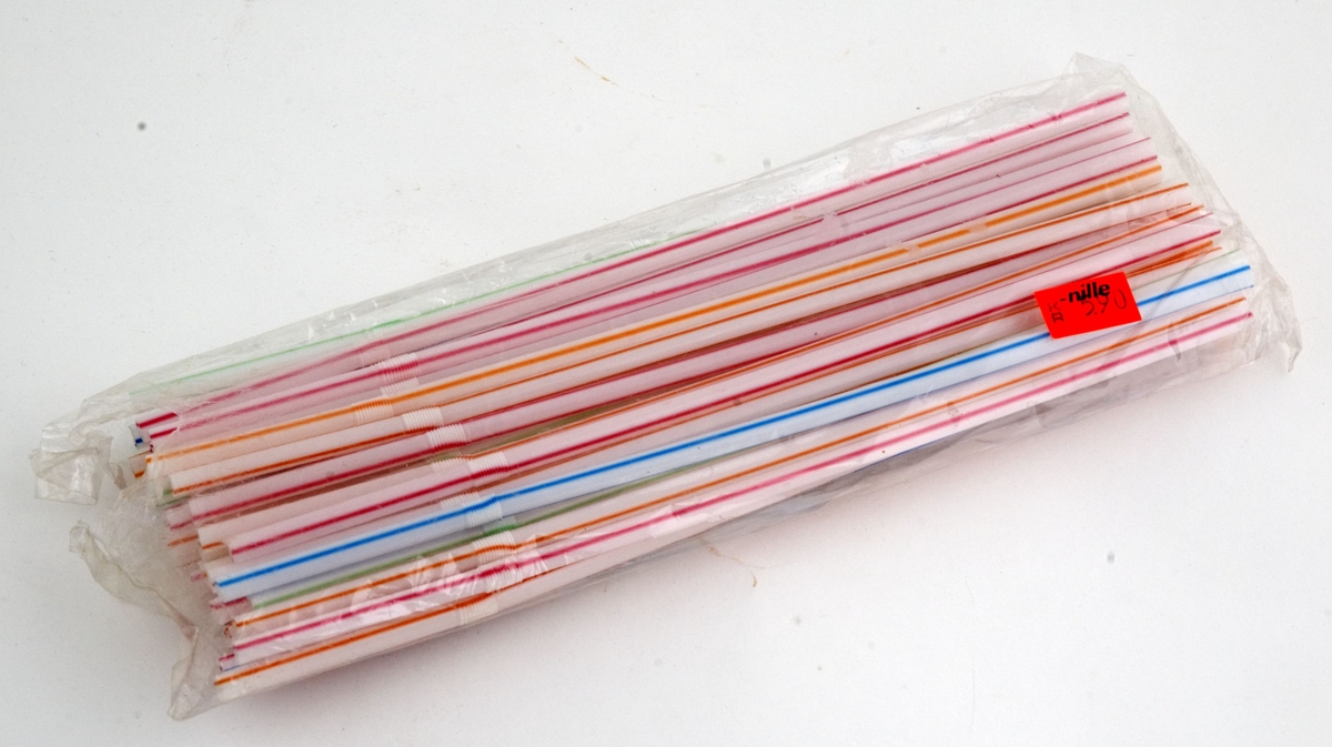 En åpnet, gjennomsiktig plastpakke med sugerør i stripet, flerfaget mønster. Prislapp fra butikken Nille er klistret på. 