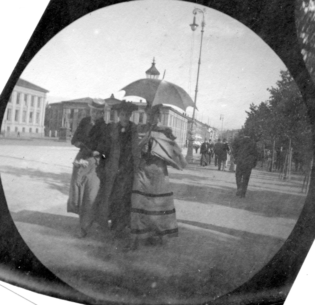 Frk. Smith, Alette Thaulow og frk. Sørbøe spaserer langs Karl Johan, Oslo, Studenterlunden med Universitetet bak.