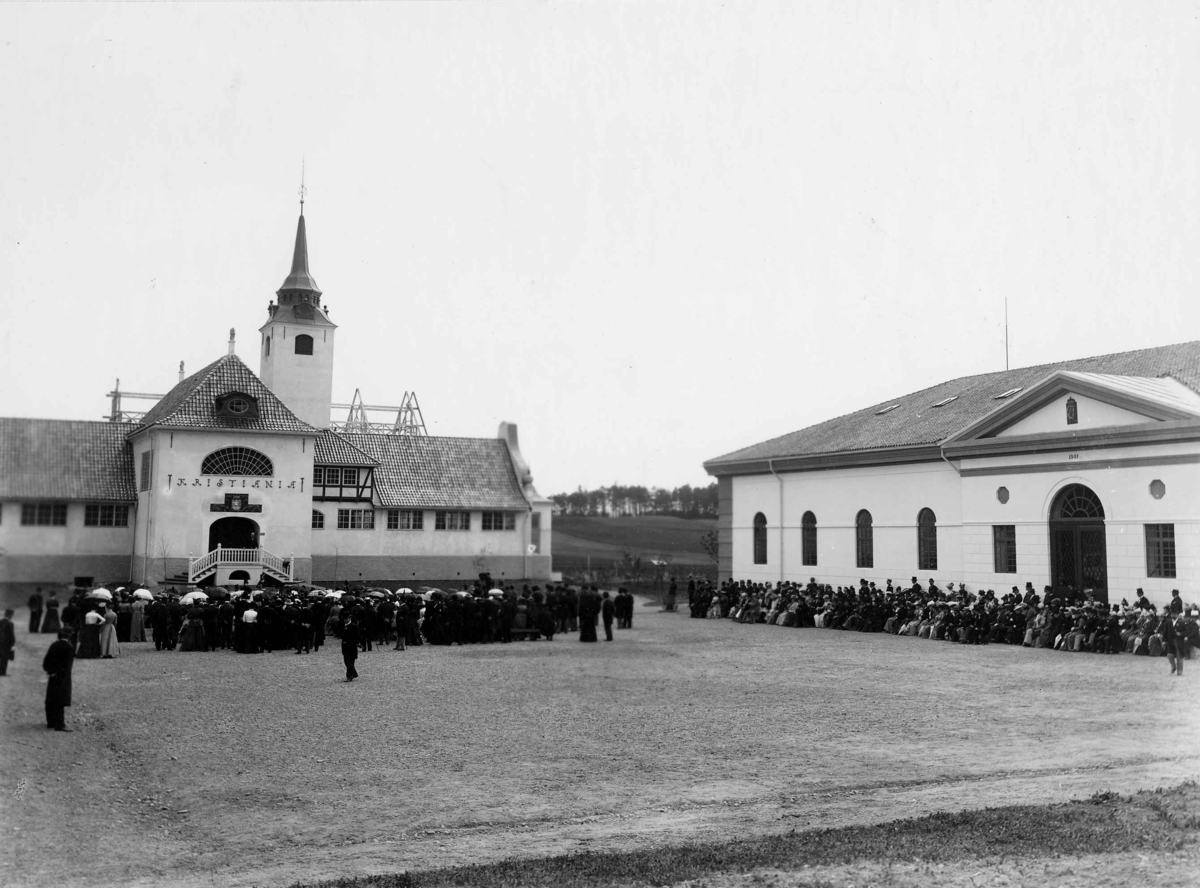 Den kulturhistoriske utstilling åpnes på Norsk Folkemuseum i Oslo 1901. Pariserpaviljongen bak kirken er ennå ikke ferdig. Mange mennesker tilstede.