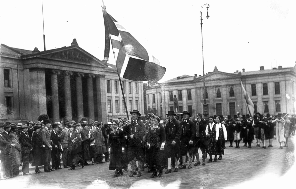 Nordisk Folkedansstevne (?), Karl Johans gate ved Universitetet - Oslo. 1925. Opptog av norske deltakere. Tilskuere.