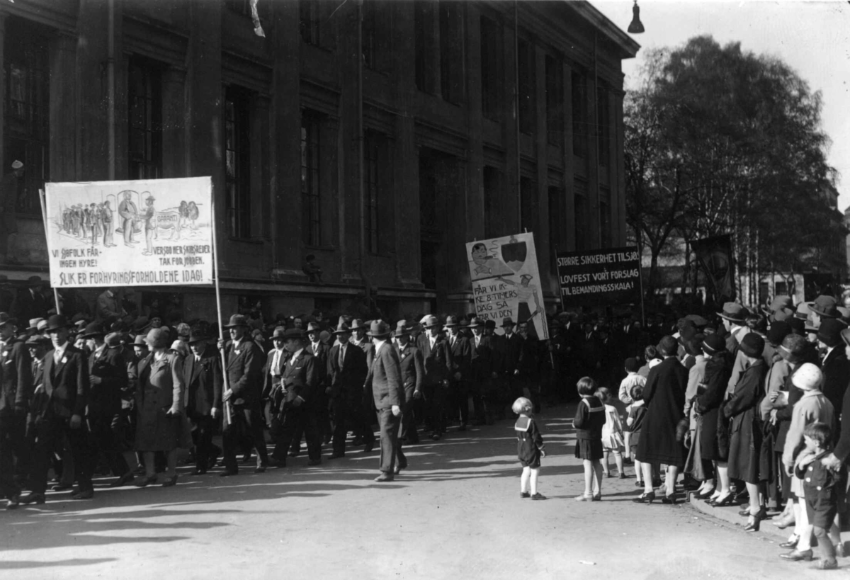 1. mai-tog i Oslo 1930. Marsjerende menn og kvinner. Paroler. Tilskuere. Barn i matrosdrakt..