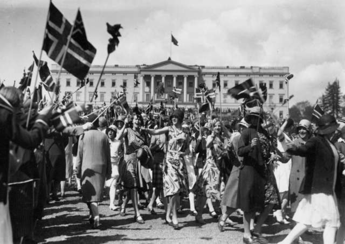 Oslo. 17. mai-tog 1930. Menn og kvinner på vei til og fra Slottet. Bærer flagg.