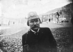 Mann med hjelm og langpipe på gårdstunet, Lunden gård, Heggl
