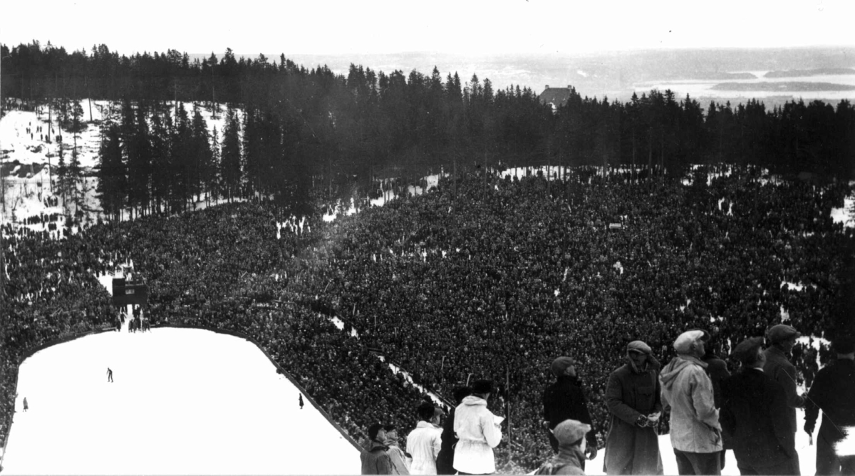 Ski. hoppreen. Holmenkollen., Oslo 1934. Oversiktsbilde over sletta og publikum. Tilskuere øverst  ved unnarennet. Oslofjorden ses i bakgrunnen.