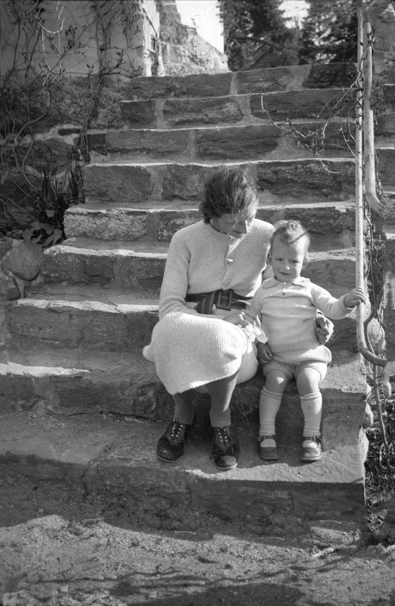 Fru Pyk sitter med sin yngste sønn på en steintrapp ved ant. villa "Solsidan" i Saltsjøbaden, Stockholm, Sverige. Fotografert 1936.