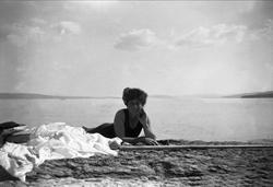 En kvinne ligger på magen på en strand. Robsahm og Lund.