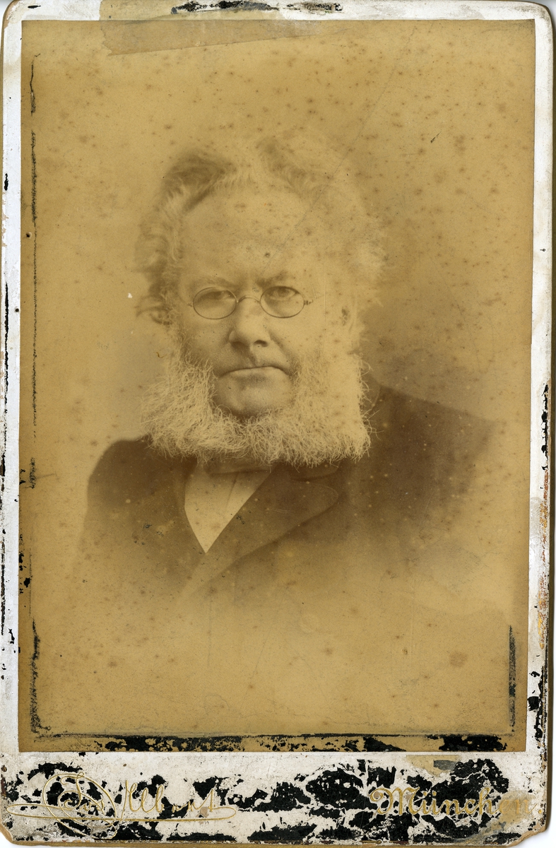 Portrett av forfatter Henrik Ibsen (1828-1906). Signert på baksiden med hilsen til fru Sofie Krohn (f. Cappelen). Fotografert i München, ukjent datering.