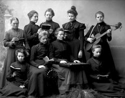 Gruppeportrett. Ni kvinner spiller gitar og zither og synger