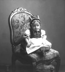 Portrett, liten pike på stol, i hardangerbunad. Fuglesangs d