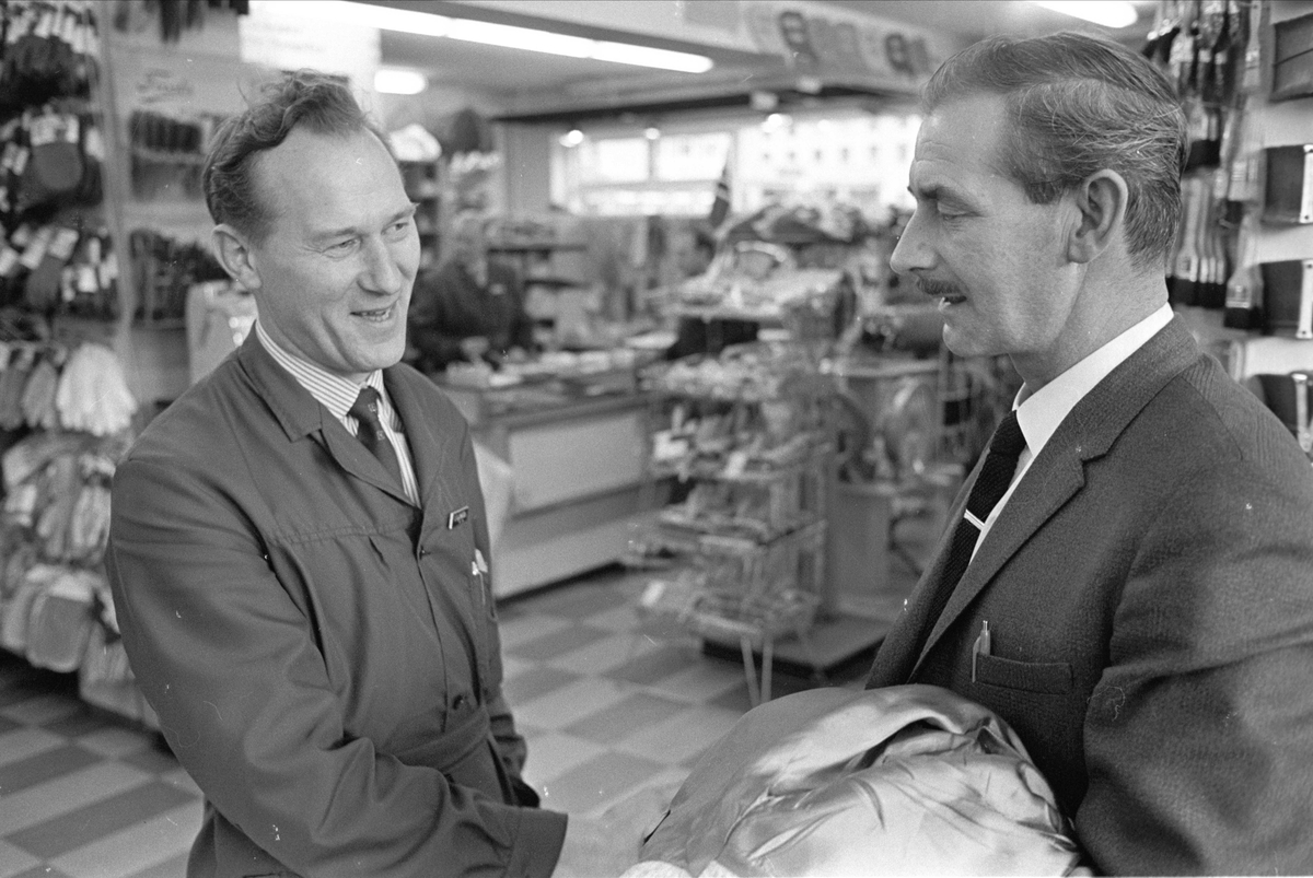 Antatt Glomfjord, Meløy, oktober 1965. Artikkel om mann fra Glomfjord-raidet, John Fairclough. Menn hilser i butikk.