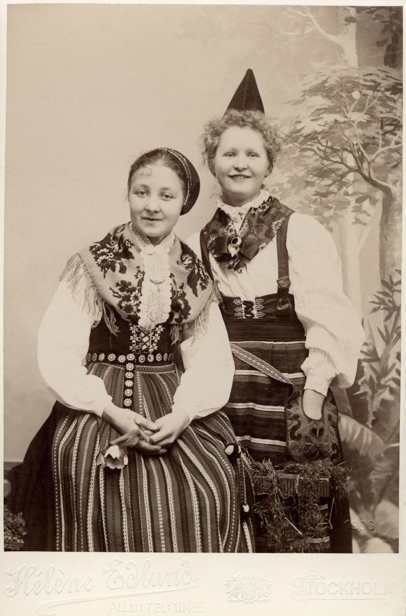 Två unga flickor poserar i folkdräkter från Dalarna.