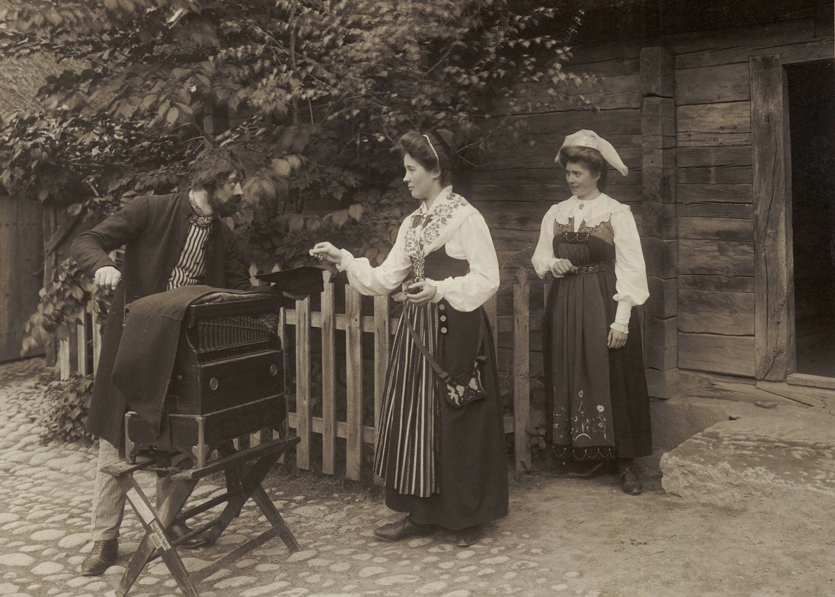 En positivhalare tar emot ett mynt av en folkdräktsklädd kvinna. Skansens vårfest 1905