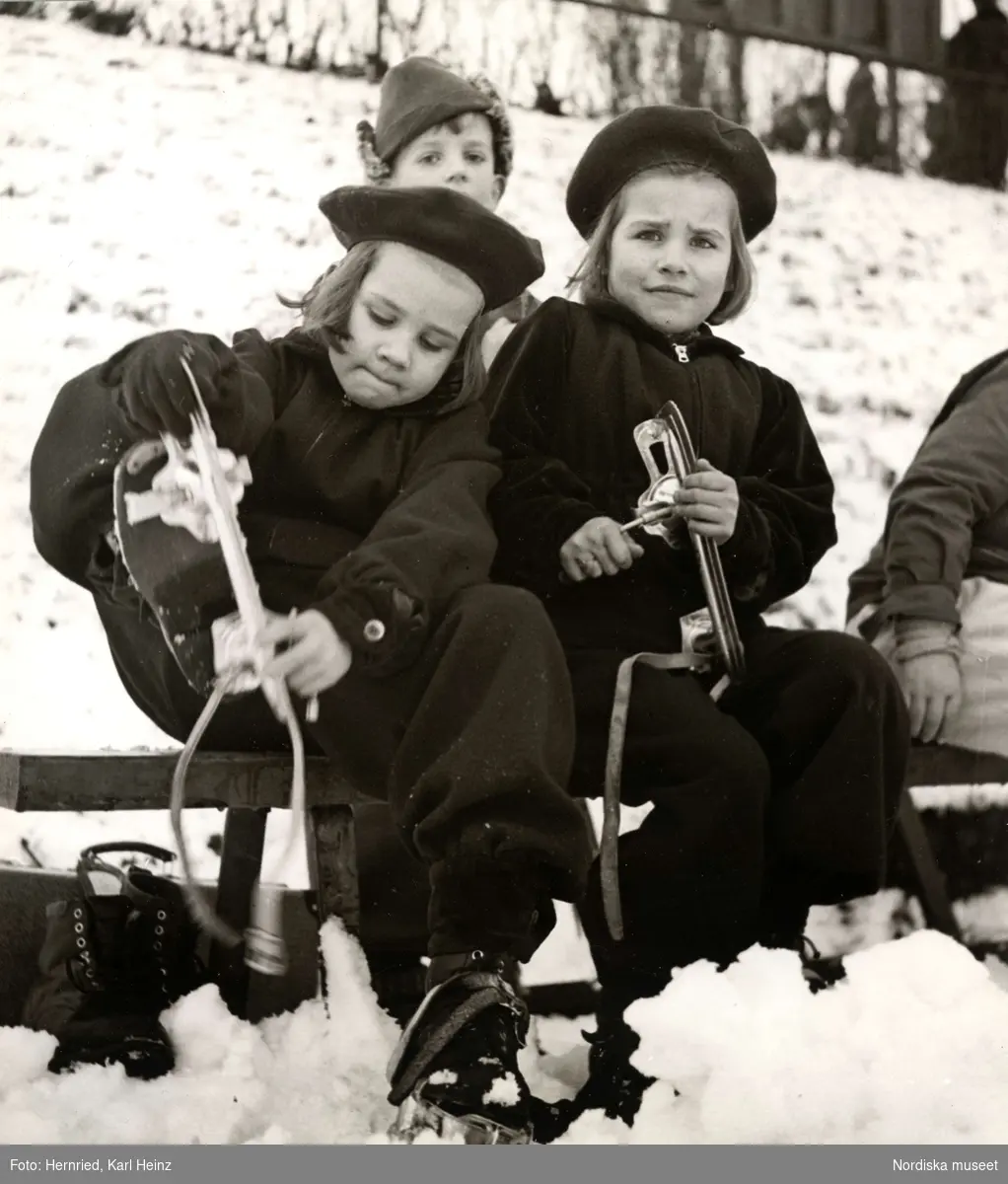 Barn sätter på sig skridskor ute i snön