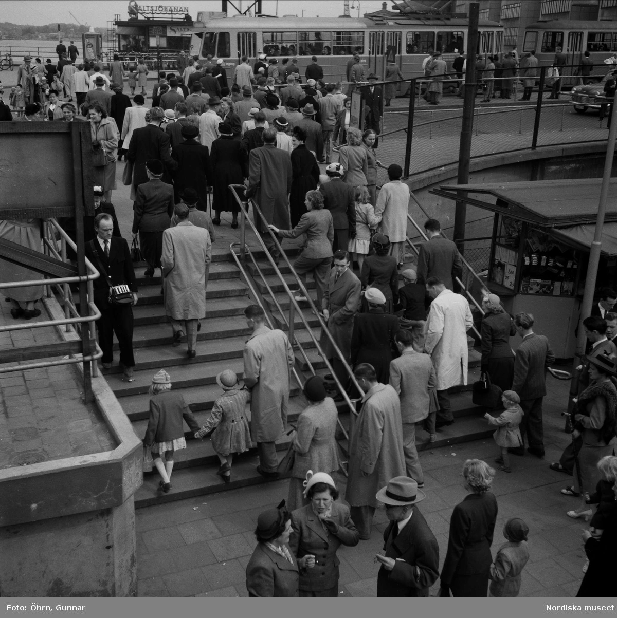 Rusningstid vid Slussen, Södermalmstorg. Människor i trappa, spårvagn i bakgrunden.