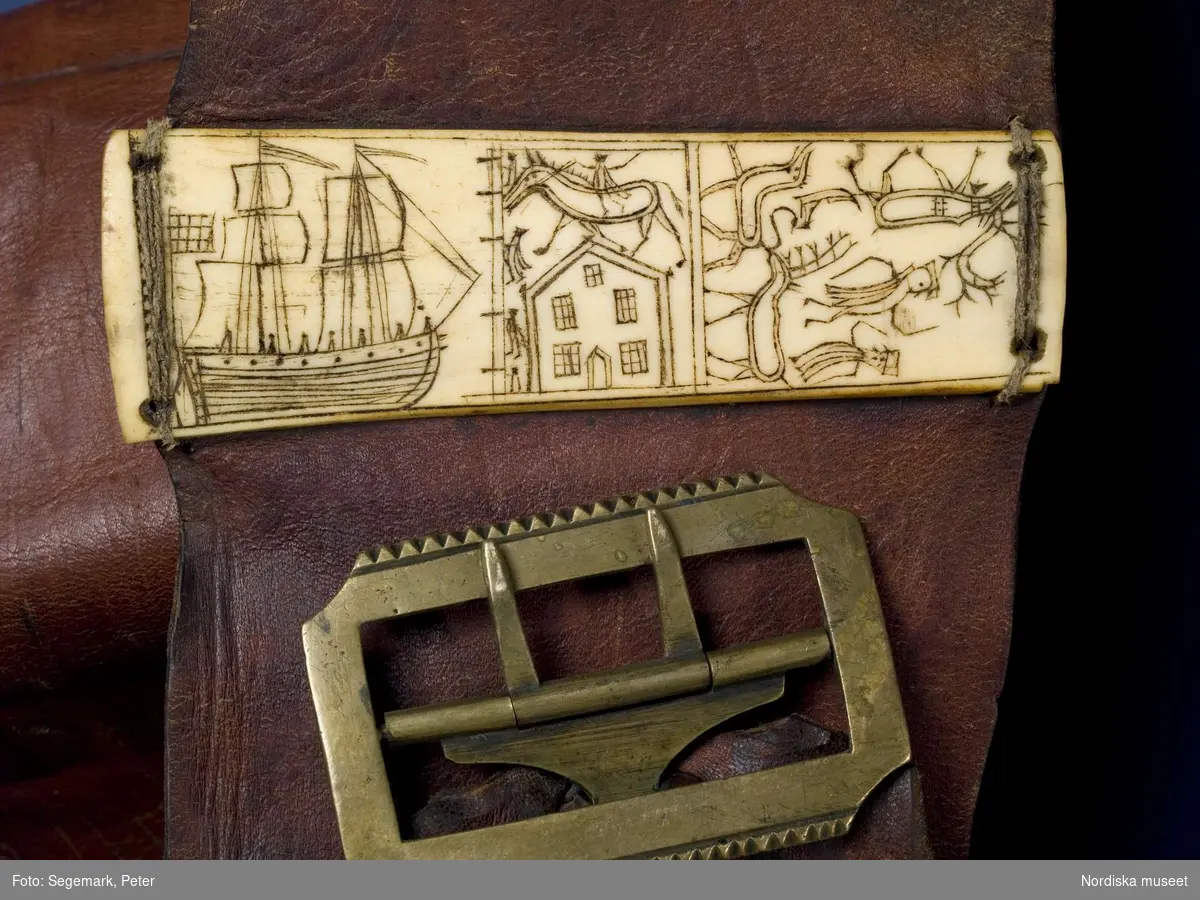Nordsamiskt bälte, detalj, platta i renhorn med graverade motiv, ett skepp,  ett hus, renar. Nordiska museets föremål inv nr NM.0074682. Jämför helbild av föremålet NMA.0048738.