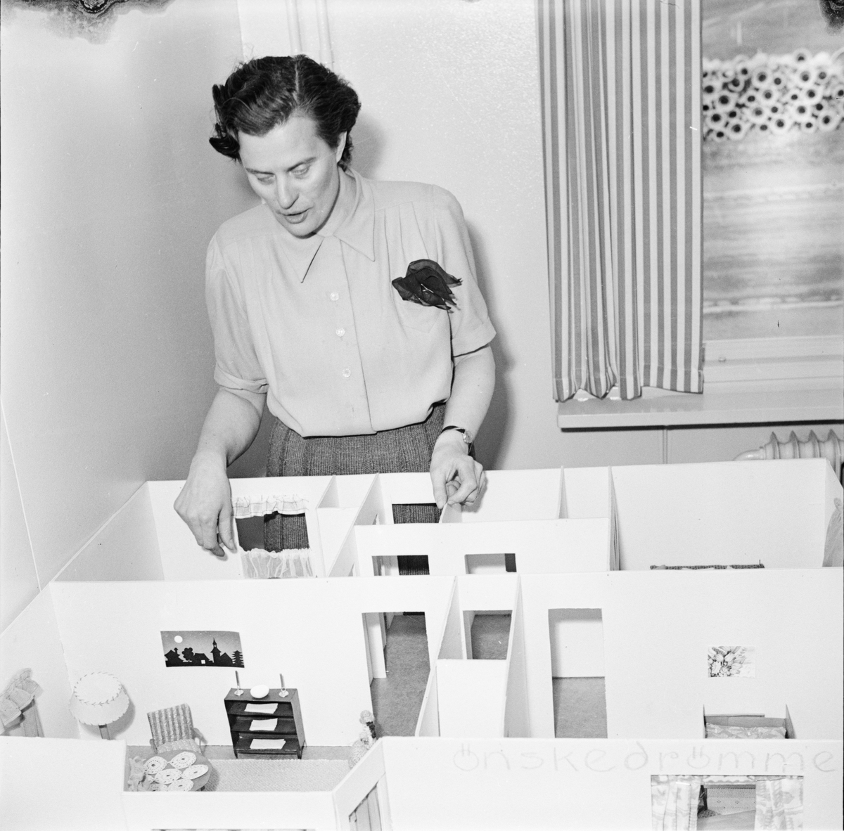 Heminredningsutställning på Gunstagatan, Uppsala april 1947.  En av studiecirkeldeltagarna vid den modell hon byggt