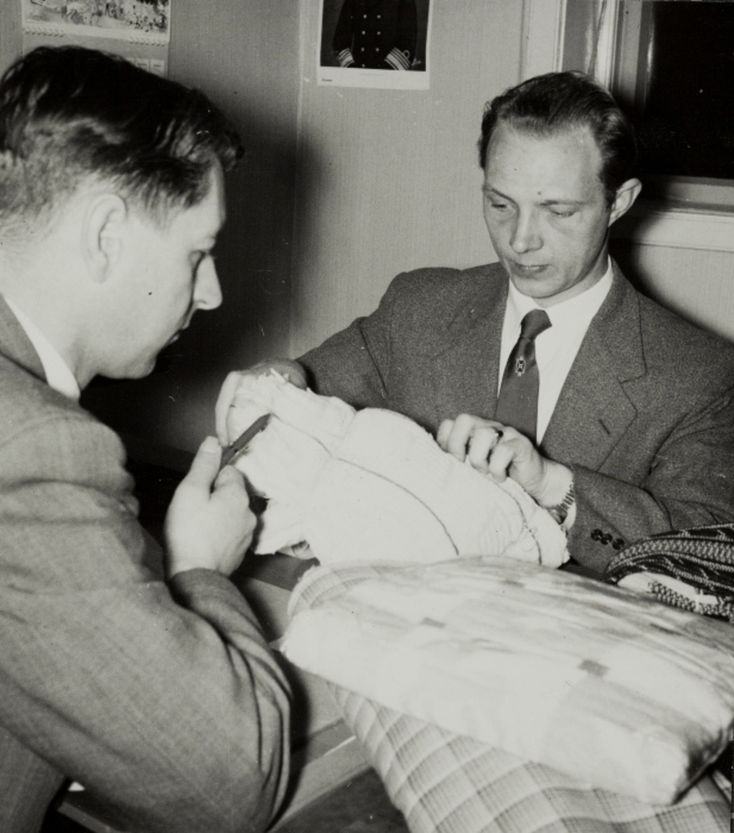 Omdahl og Eikeland ser igjennom tekstiler mens de forbereder katalogen i anledning vårsalget i 1957.
