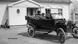 Familien Astrup fotografert i en T-Ford foran våningshuset p
