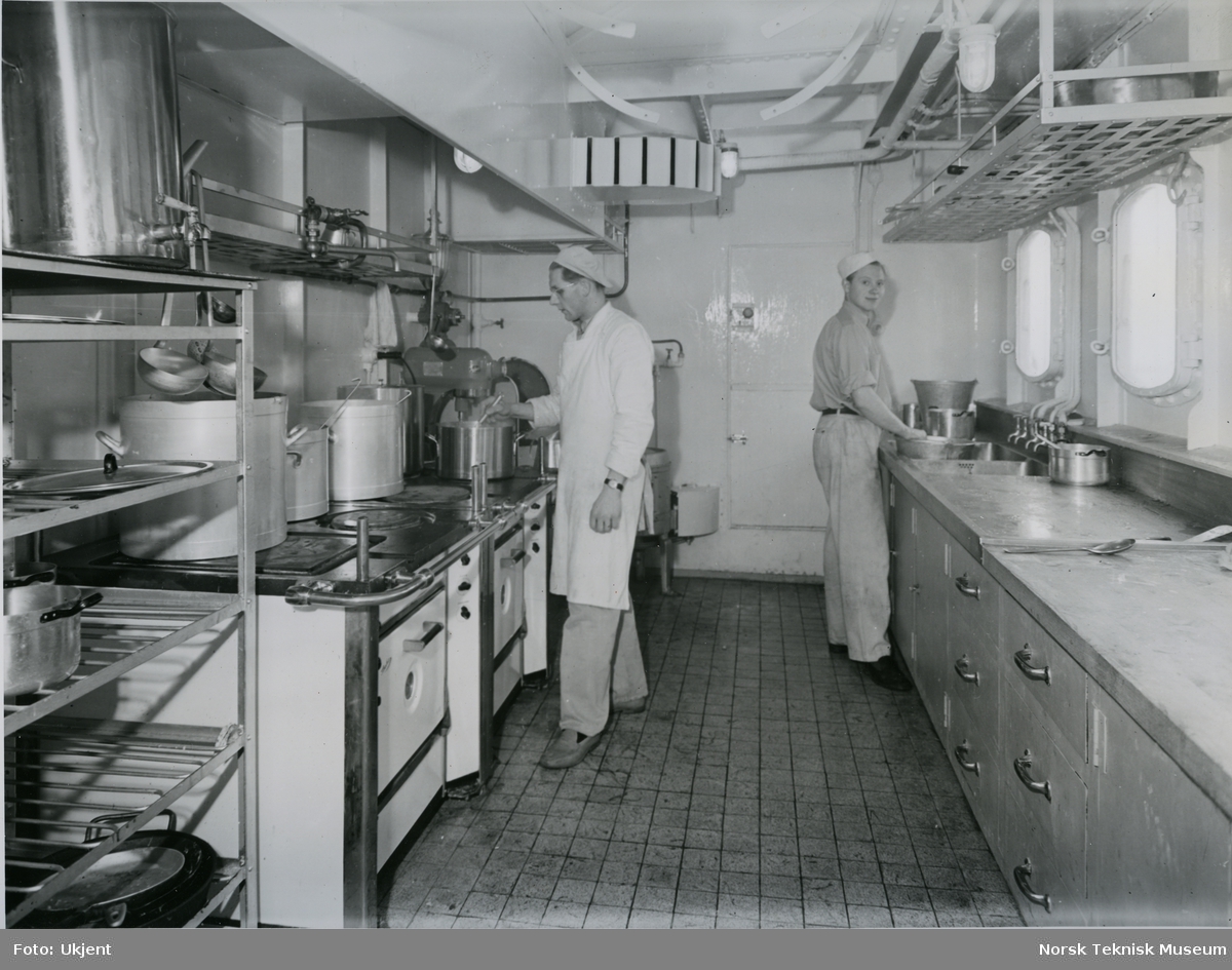 To kokker som lager mat på cargolineren M/S Tabor, B/N 492. Skipet ble levert av Akers Mek. Verksted i 1952 til Wilh. Wilhelmsen.