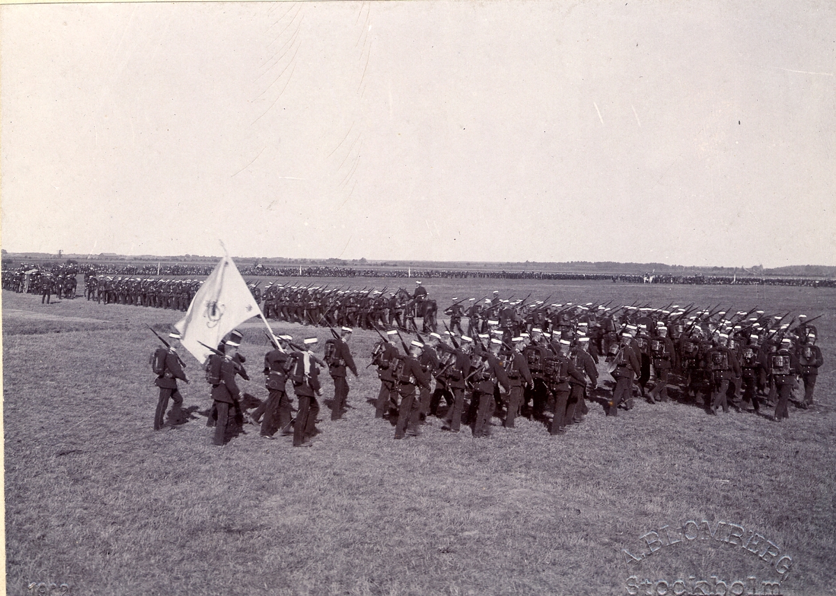 Göta livgarde I 2 ute på marsch 1902. Soldaterna bär uniform m/1886 och är utrustade med full packning. Längst bak går soldat med regementets fana.
