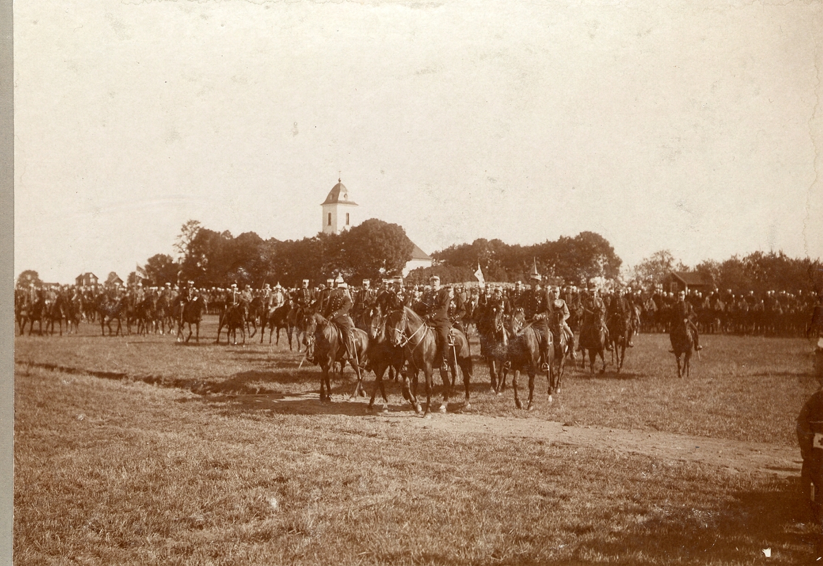 Kavalleritrupp ledd av kung Oscar II framför kyrka.