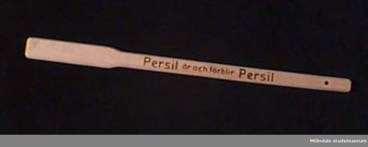 Tvättkäpp i förpackning - båda märkta: "Persil är och förblir Persil" ( i svart tryck). Förpackningen trasig, käppen oanvänd. Märkt med tusch (?) på baksidan: "Hulda Olausson". Har tillhört givarens svärföräldrar som tvättade i Persil och lade i blöt i Henko. Utdelad i samband med reklamfilm på 1930-talet.Tvättkäppar användes för att trycka ned tvätten och röra om den i vattnet. Att den inte kom till användning berodde på att i bostadsområdet i Kålltorp där ägaren bodde så fanns det tvättutrustning i tvättstugan.